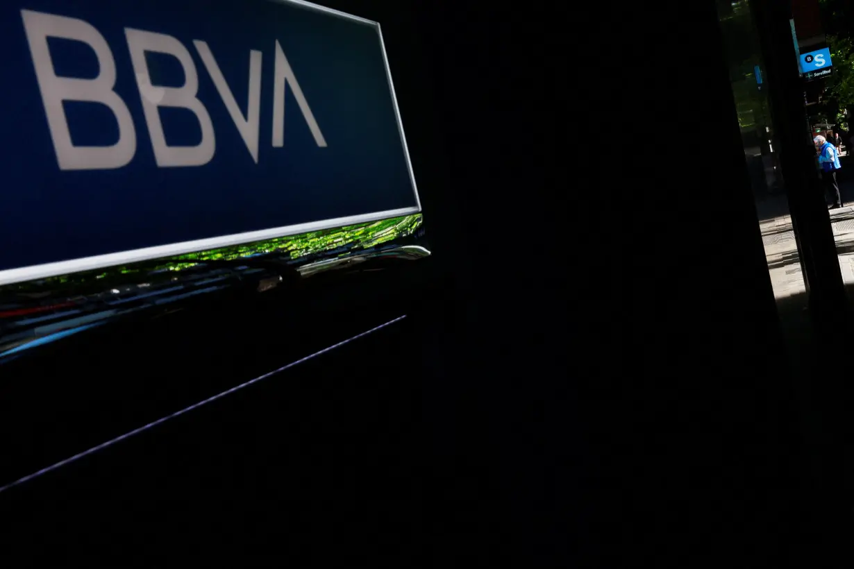 A man uses an ATM machine of Spain's Sabadell bank near a branch of Spain's BBVA bank in Madrid