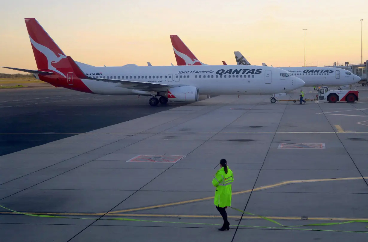 FILE PHOTO: Workers are seen near Qantas Airways, Australia's national carrier, Boeing 737-800 aircraft on the tarmac at Adelaide Airport