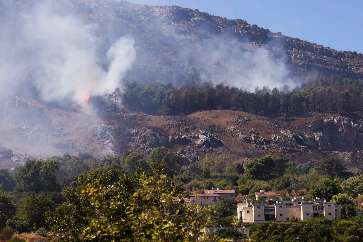 Smoke and flames are visible near homes in Kiryat Shmona after a rocket attack launched from Lebanon