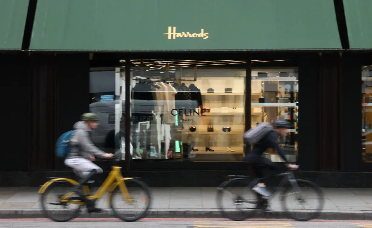 People cycle by the Harrods department store, in London