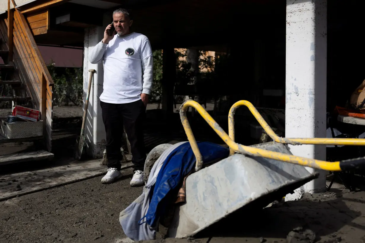 Syrian migrants help with the clean-up after the floods