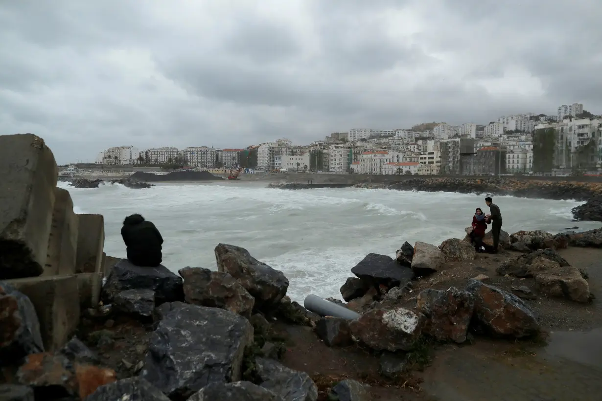 People are pictured in the rainy day on the edge of the Ketani beach at Bab El Oued in Algiers