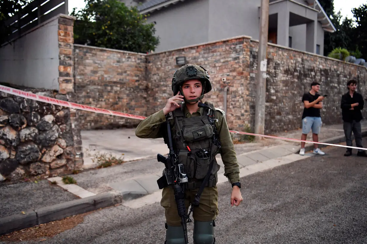 An Israeli soldier uses her phone at the site where a rocket fired from Lebanon into Israel hit a residential house, in Rosh Pina