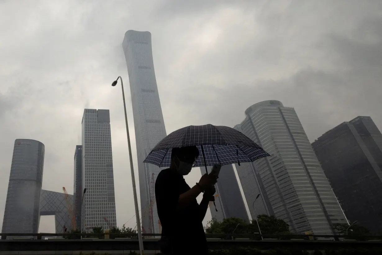 FILE PHOTO: A man walks in the Central Business District on a rainy day, in Beijing