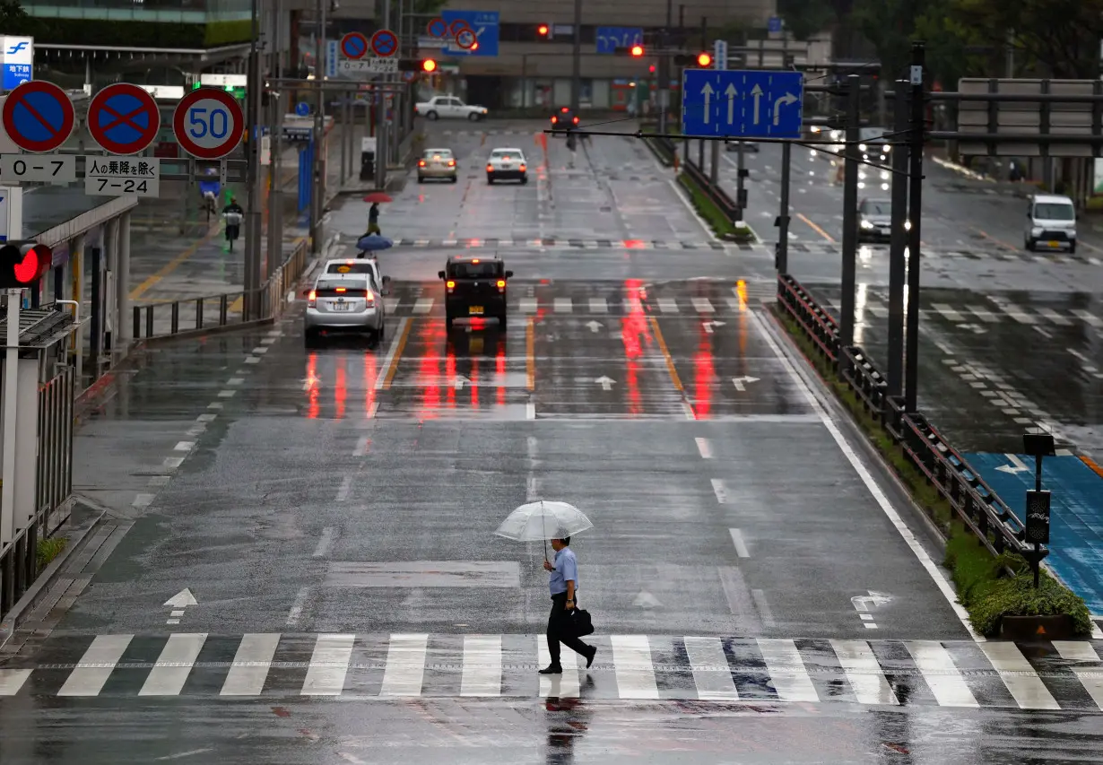 Passersby holding umbrellas walk on the street in the rains and winds caused by Typhoon Shanshan in Fukuoka