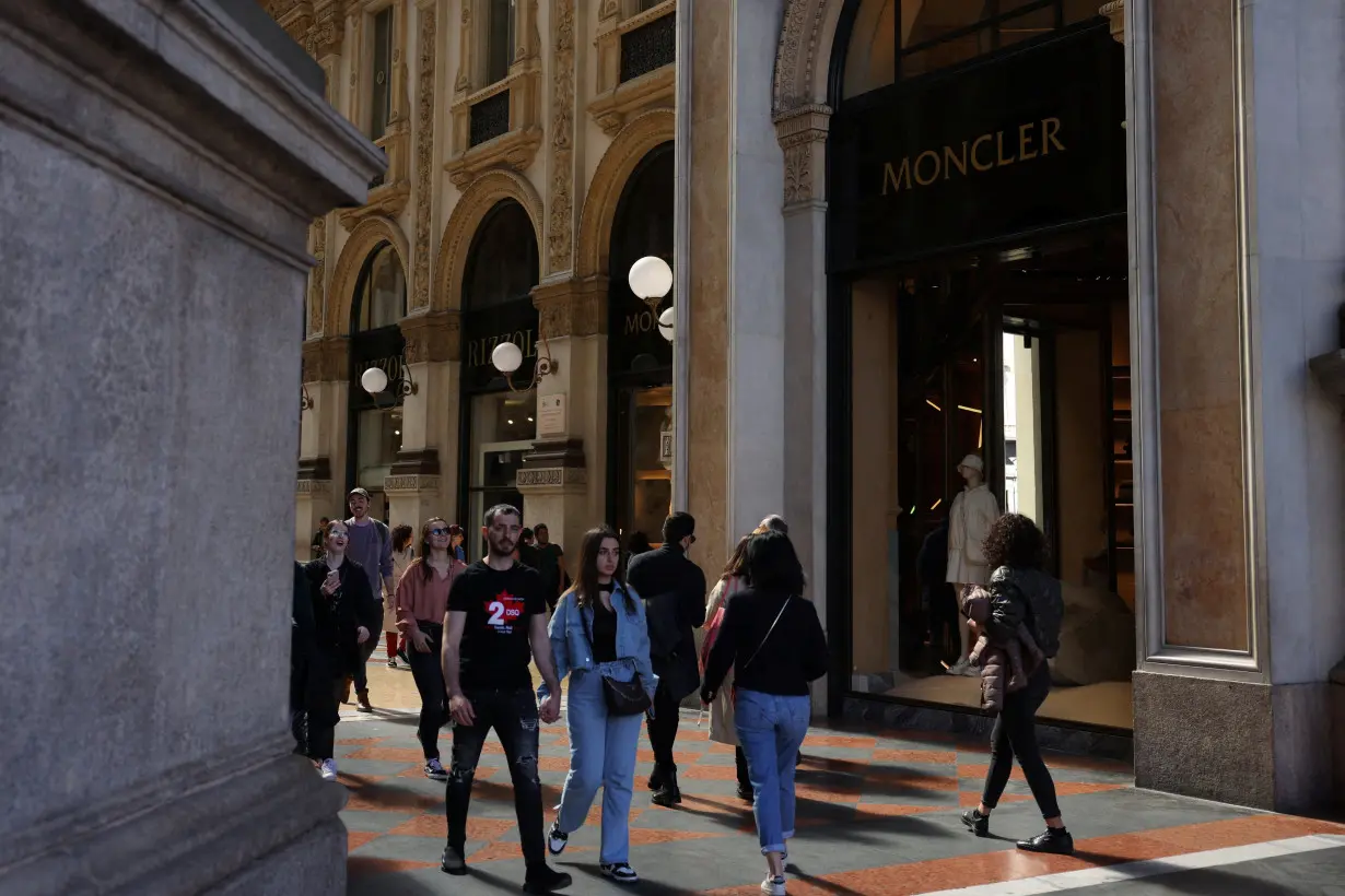 People walk next to a Moncler shop in Galleria Vittorio Emanuele II, in Milan