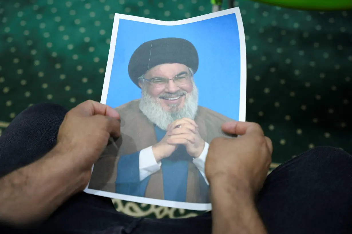 An Iraqi volunteer holds a picture of Lebanon's Hezbollah leader Nasrallah while registering his name to support Hezbollah, in Basra