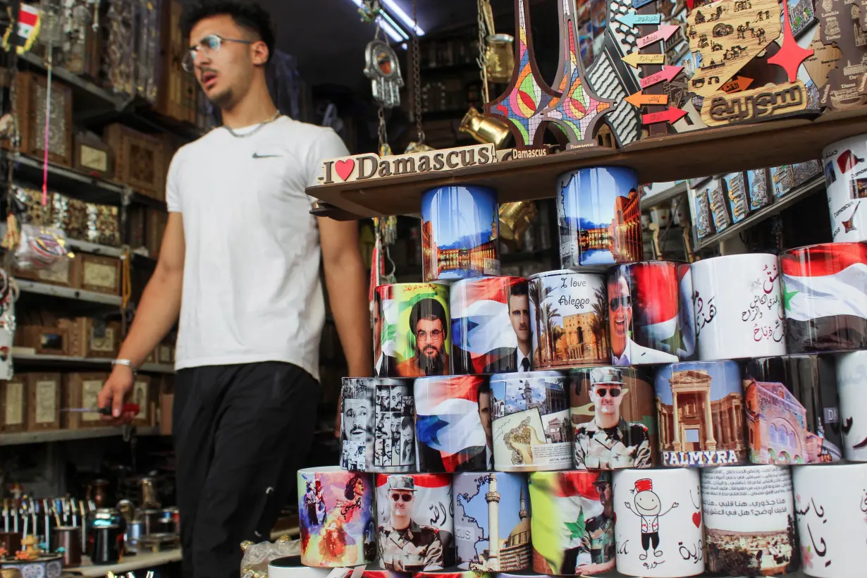 A man walks past mugs featuring pictures of Syrian President Bashar al-Assad and Lebanon's Hezbollah leader Sayyed Hassan Nasrallah, who was killed in an Israeli airstrike on Friday, at a souvenir shop during national mourning for Nasrallah, in Damascus