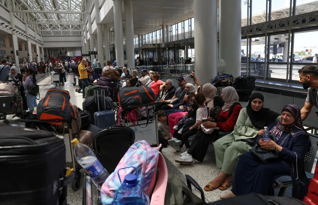 People sit near their luggages at the Beirut–Rafic Hariri International Airport, in Beirut