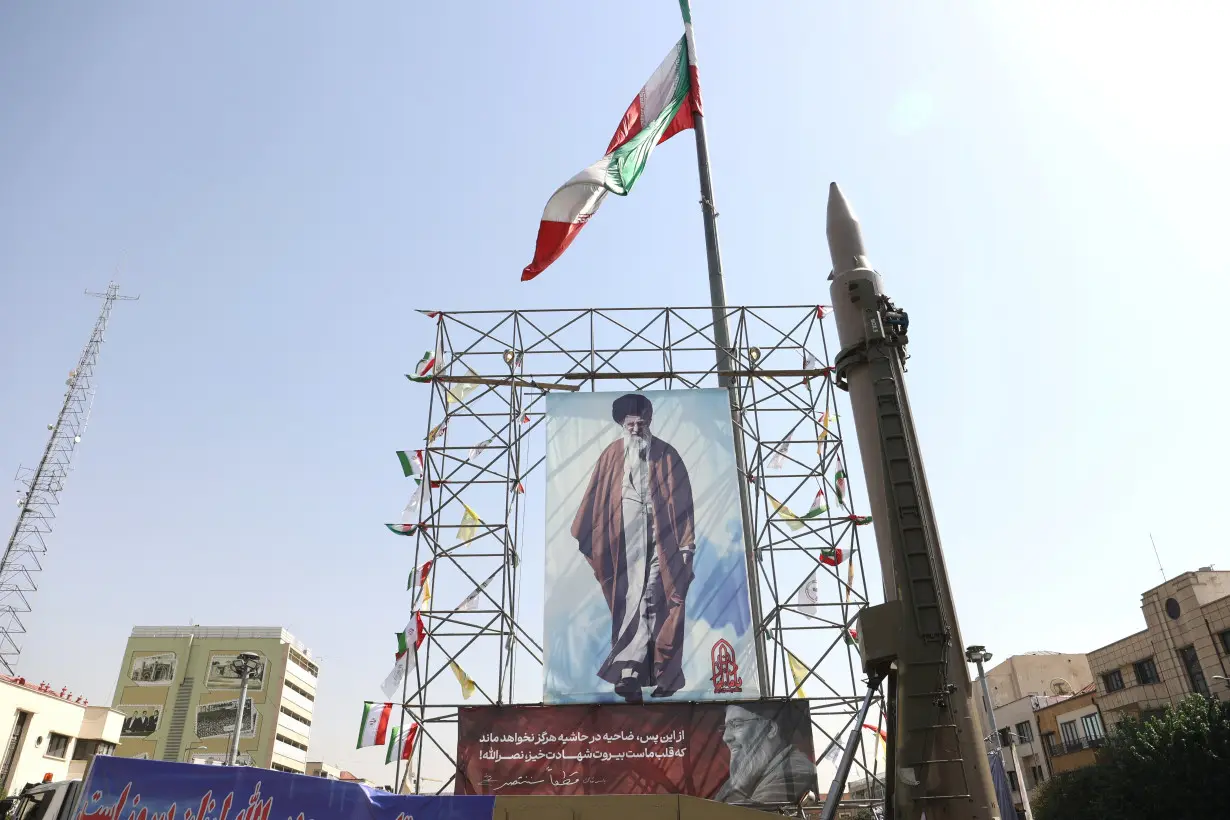 An Iranian missile system is displayed next to a banner with a picture of Iran's Supreme Leader Ayatollah Ali Khamenei and the late Lebanon's Hezbollah leader Hassan Nasrallah, in a street in Tehran