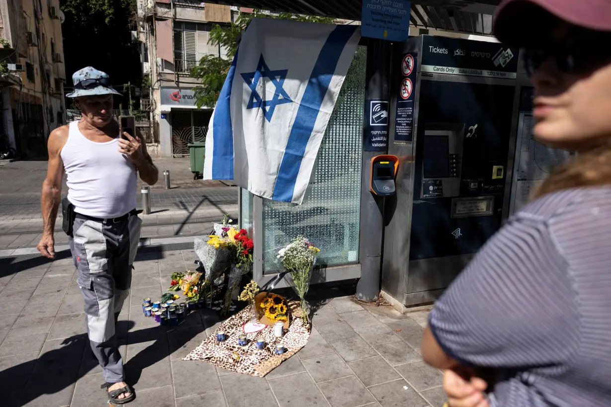 A man walks by flowers laid as a sign of respect for the people killed the evening before in a fatal shooting attack in Jaffa