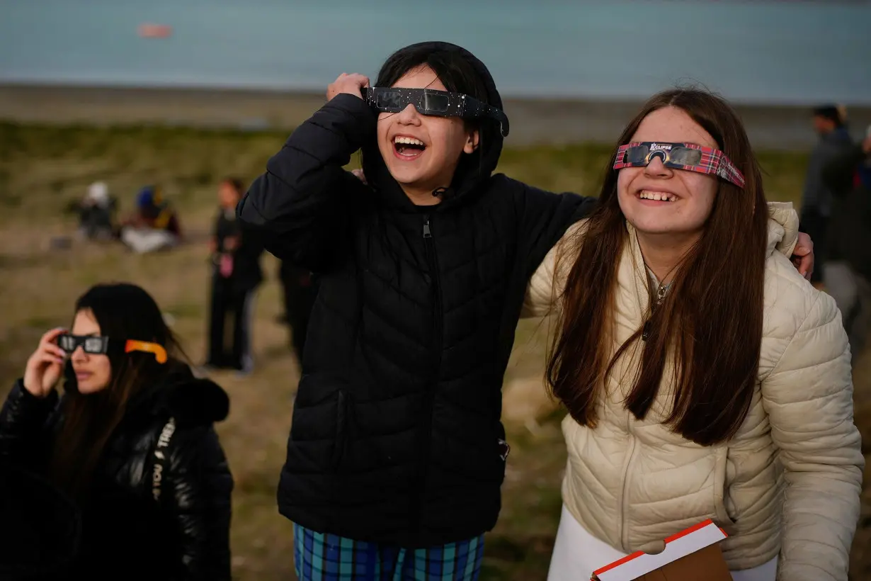 People watch as an annular solar eclipse appears Wednesday in the sky over Puerto San Julián, Argentina.