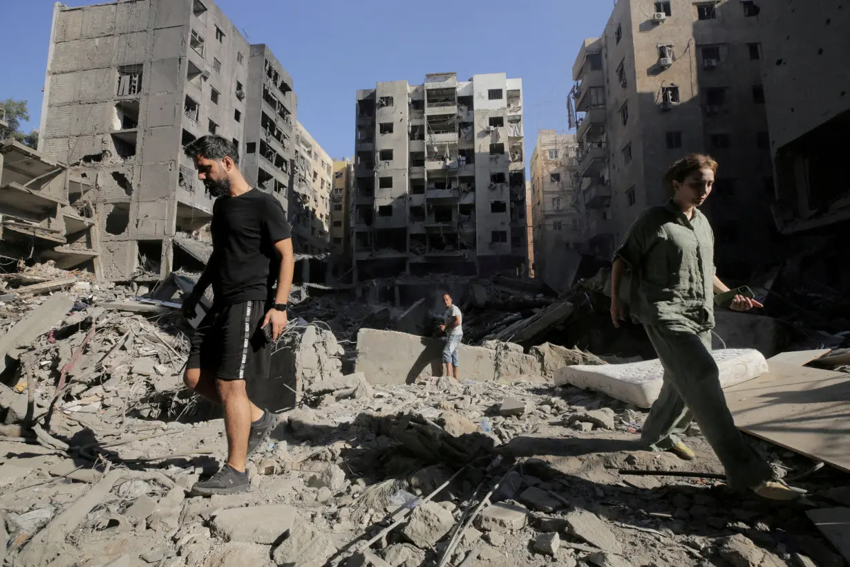 FILE PHOTO: People walk on the rubble at the site of the Israeli airstrike that killed Lebanon's Hezbollah leader Sayyed Hassan Nasrallah on Friday, in Beirut's southern suburbs