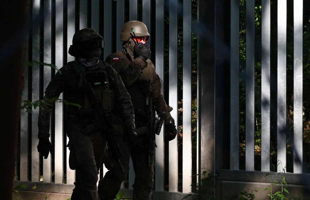 Polish soldiers walk near the fence on Belarusian-Polish border in the forest near Topilo village