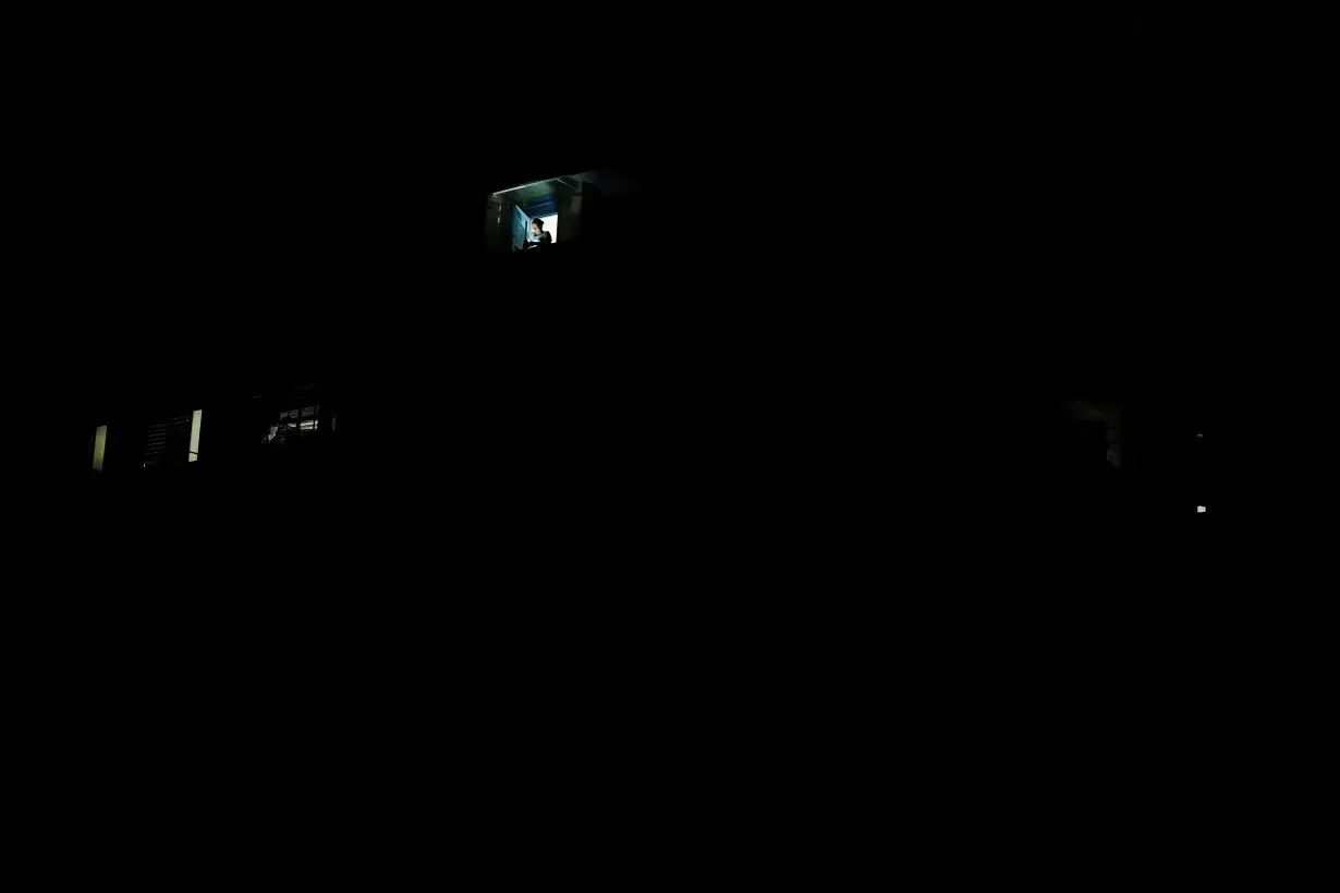 FILE PHOTO: A woman stands on a window during a blackout, in Santiago