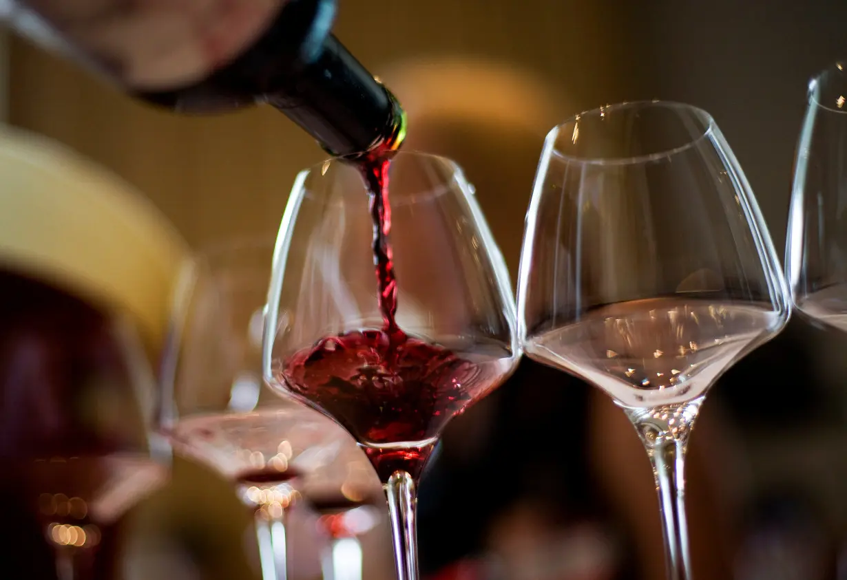 A waiter serves a glass of red wine