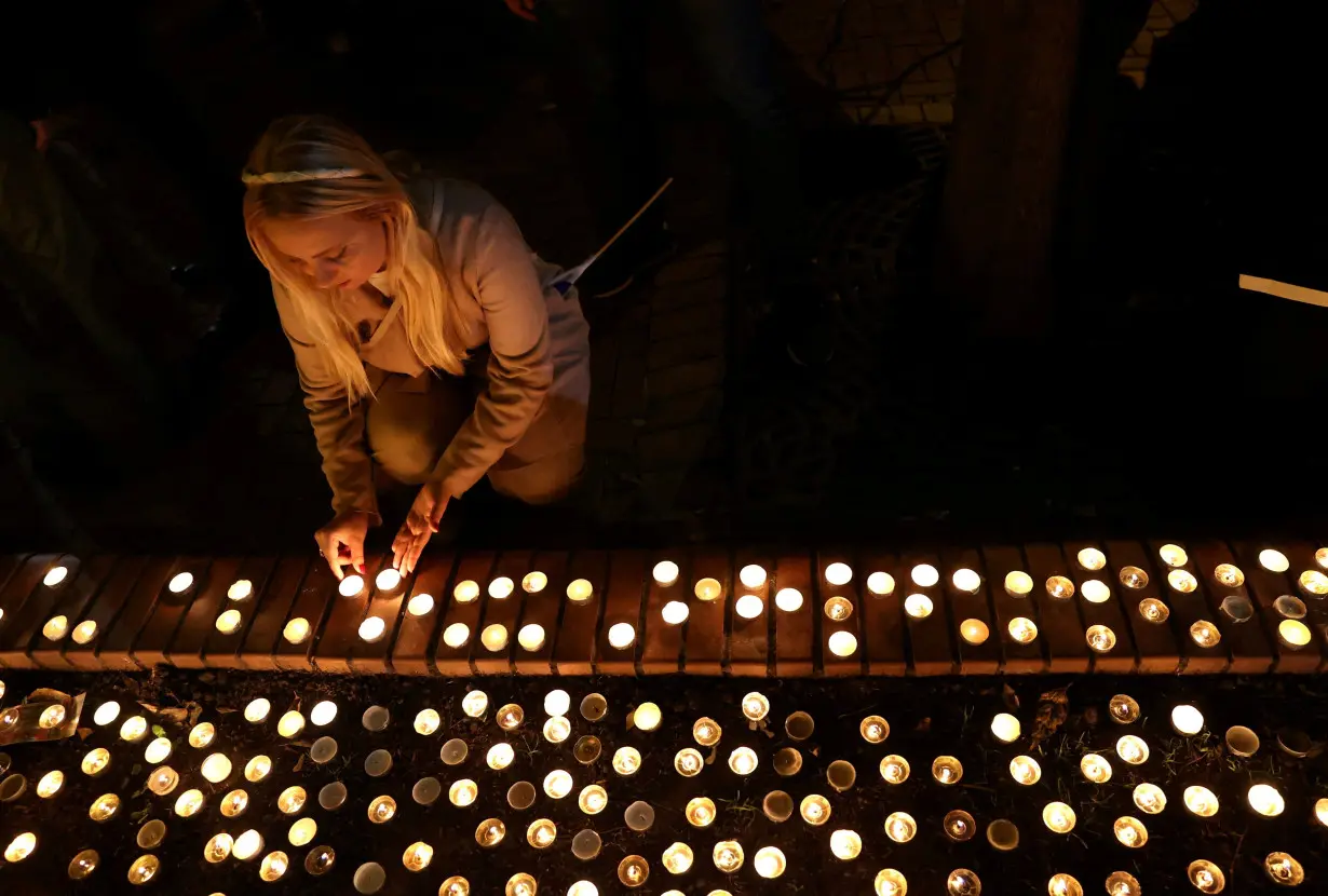 A woman lights a candle during a commemoration of the first anniversary of the October 7 Hamas attacks on Israel at the the Dohany Street Synagogue in Budapest