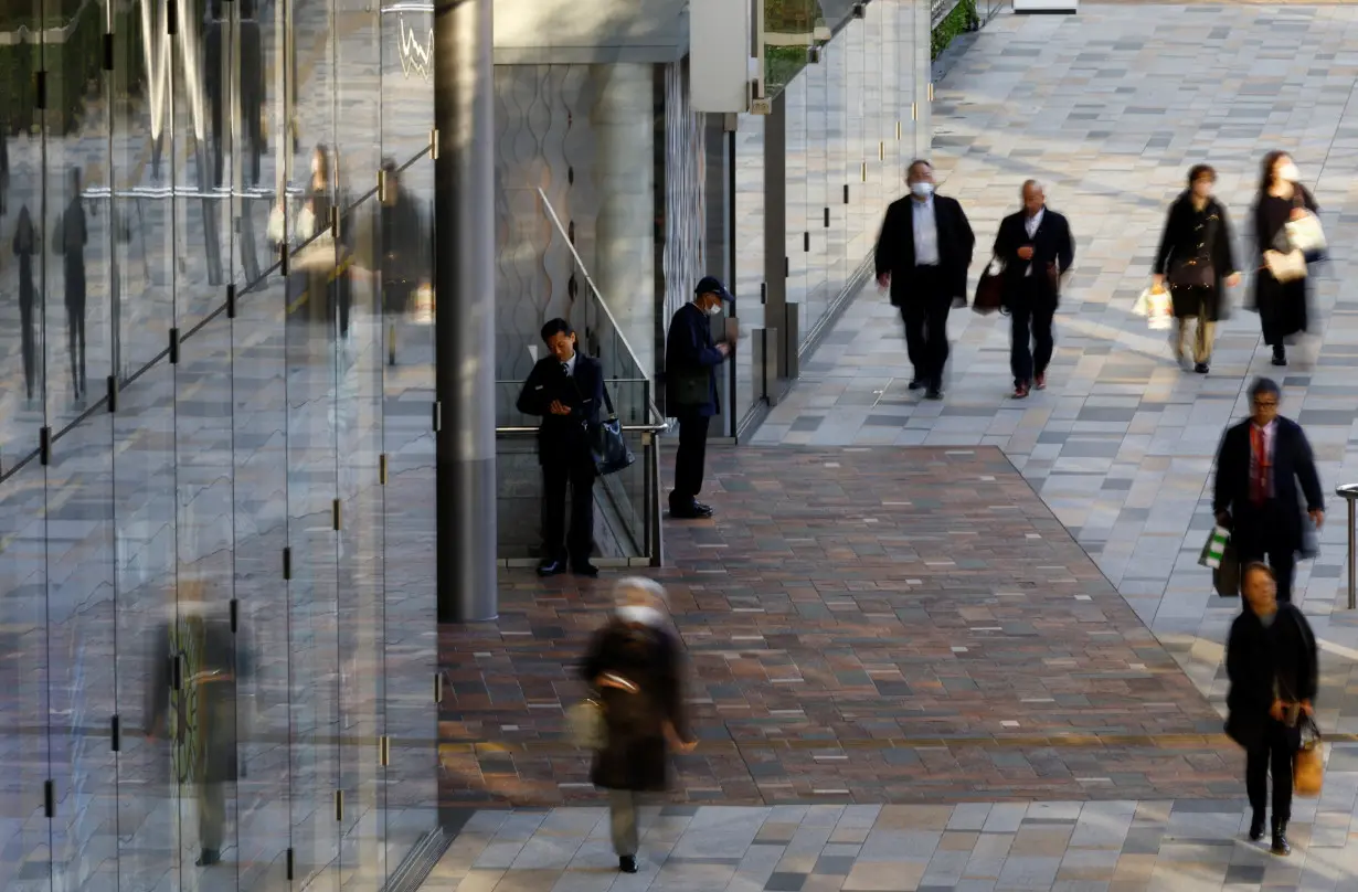 A man works with a laptop on a street at a business district in Tokyo