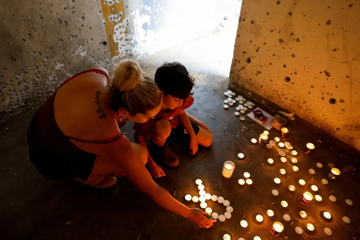 A boy and his mother light memorial candles inside a bomb shelter in which people were killed during the deadly October 7 attack by Hamas on the first anniversary since the attack, near Kibbutz Mefalsim in southern Israel, on October 7.