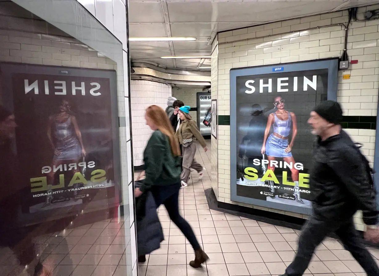 FILE PHOTO: People walk past an advertisement for Shein