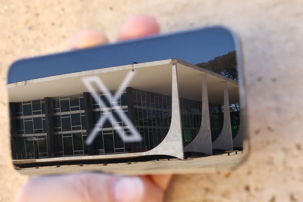 The logo of social media platform X is seen on a mobile phone next to a reflection of Brazil's Supreme Court in this illustration taken August 30, 2024, in Brasilia