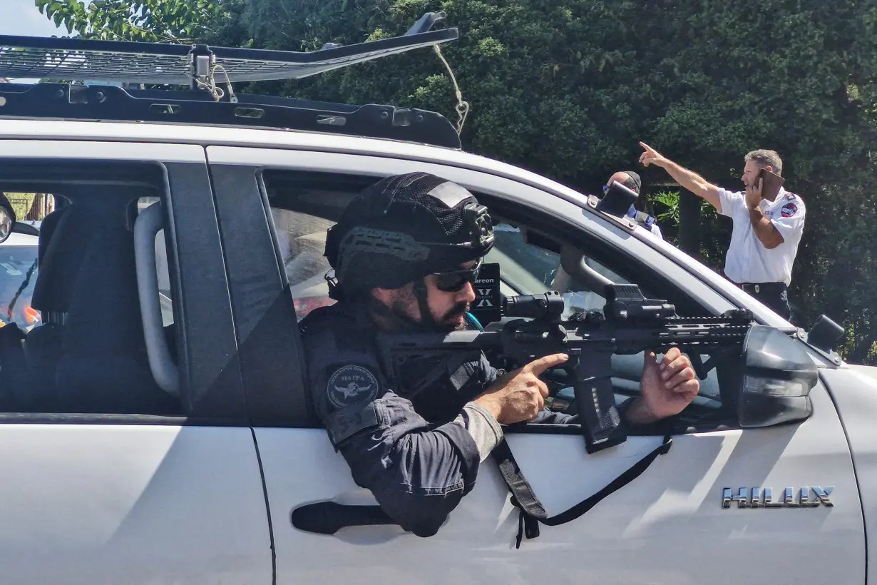 An Israeli police officer aims his weapon from a vehicle following a suspected stabbing attack in Hadera