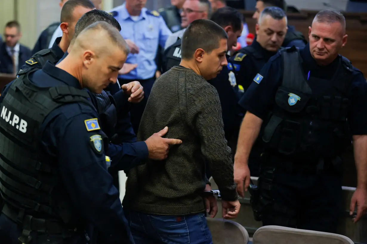 Kosovo police officers escort the alleged Serbian gunman Dusan Maksimovic at the basic court in Pristina