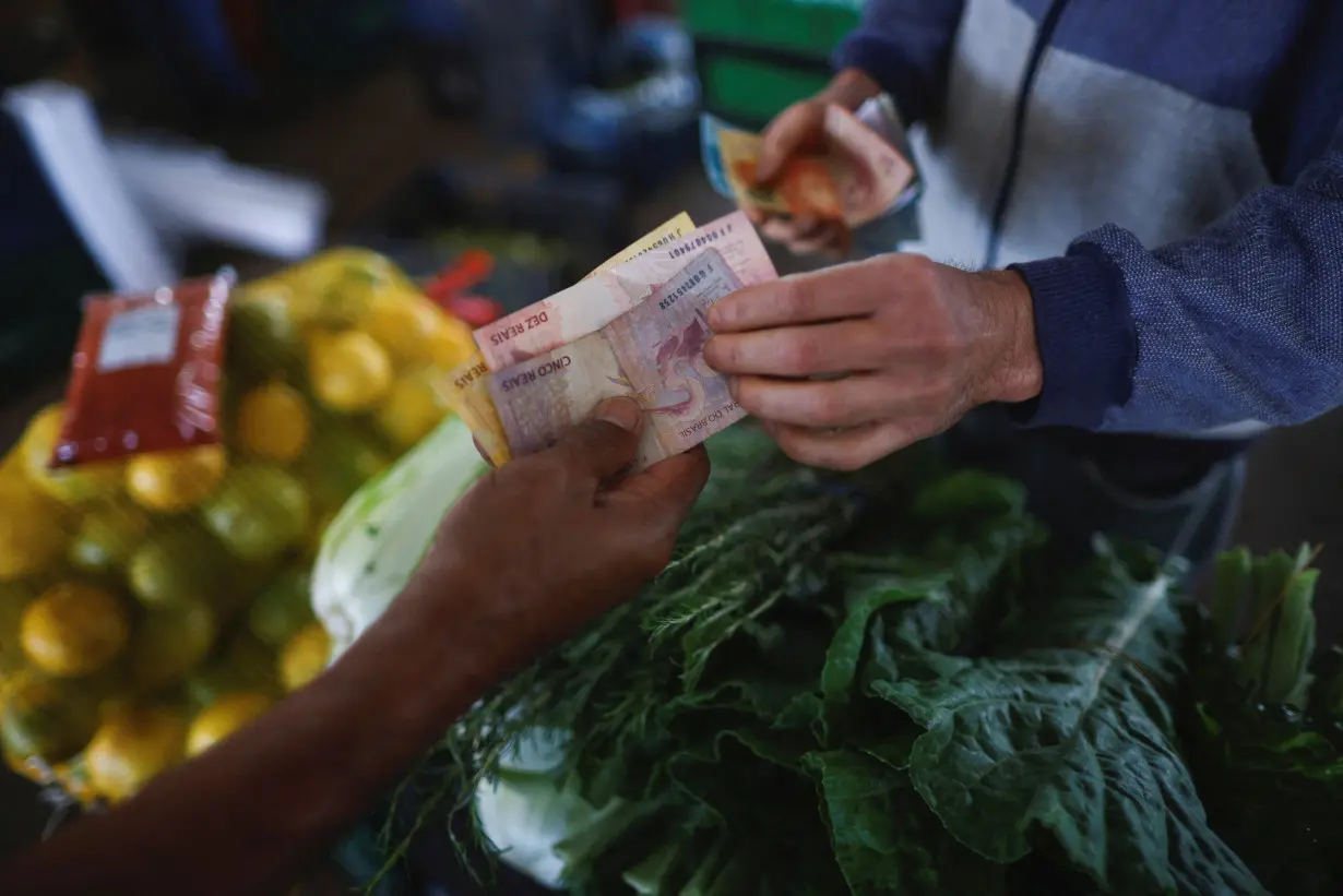 A man pays a vendor at a fruit stand, at a supply centre (CEASA) in Brasilia