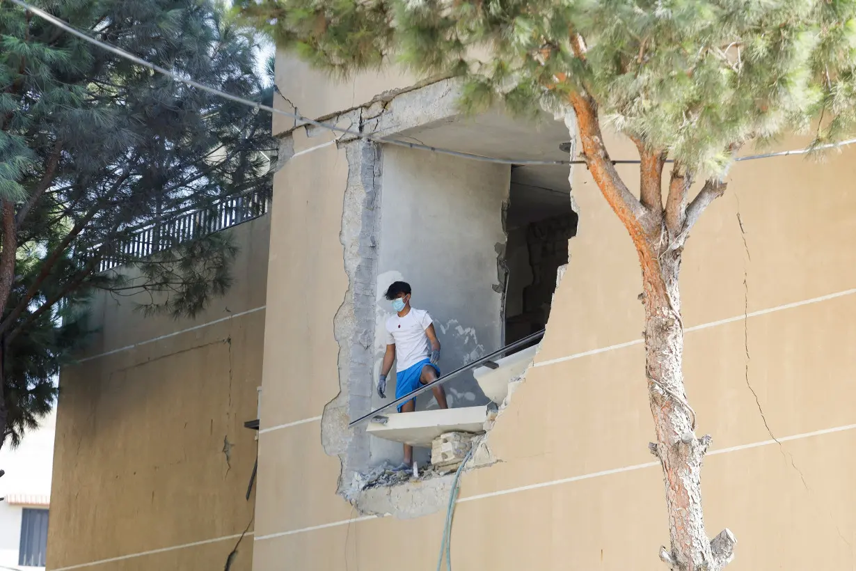 A man stands on a damaged building in the aftermath of an Israeli strike that hit a building, in Wardaniyeh