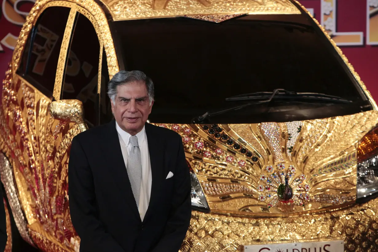 Chairman of Tata Group Ratan Tata poses in front of a Nano car made of gold during a ceremony in Mumbai