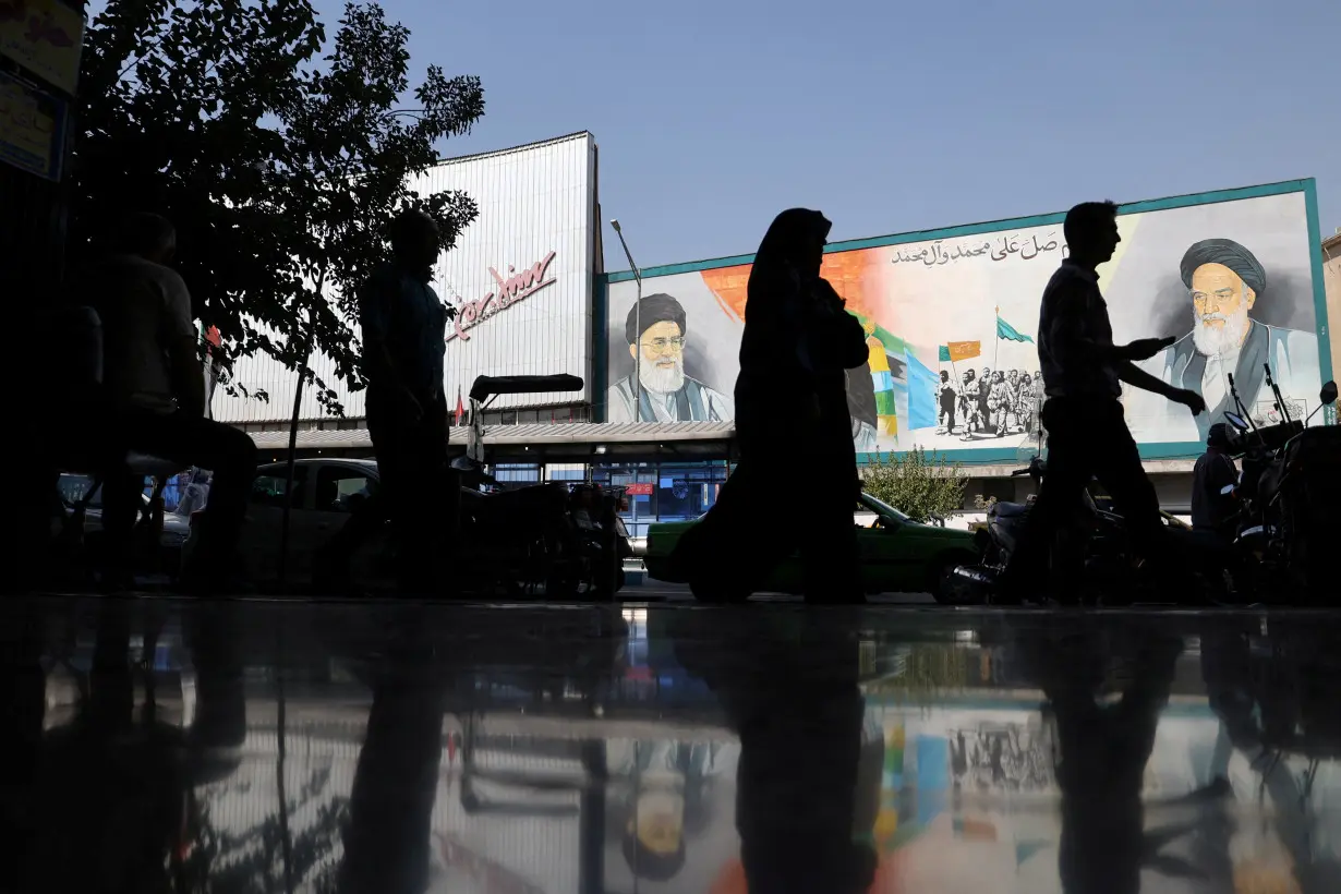 FILE PHOTO: People walk past a mural depicting the late leader of the Islamic Revolution Ayatollah Ruhollah Khomeini and Iran's Supreme Leader Ayatollah Ali Khamenei on a building in a street in Tehran