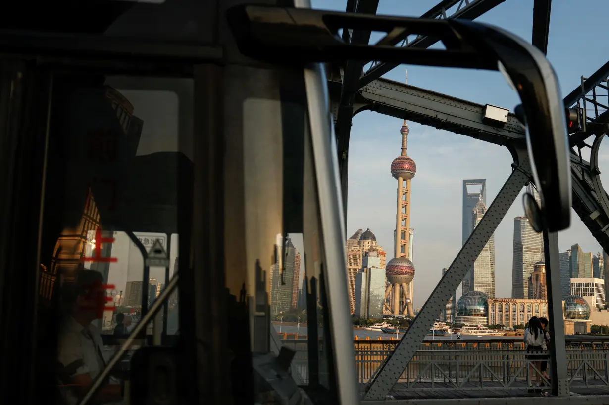 A bus moves past a bridgewith the backdrop of the financial district of Pudong in Shanghai