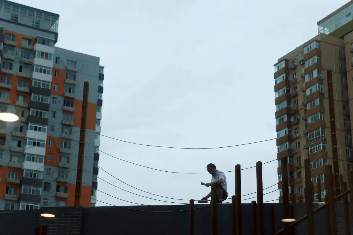 Man works on renovating an office building near residential buildings in Beijing