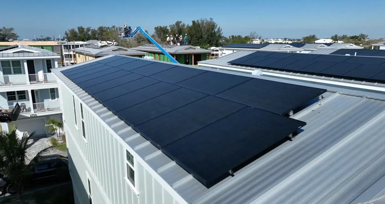 Construction workers are seen securely attaching solar panels to the roofs' raised vertical seams to prevent them from flying off during violent storms in April 2024.