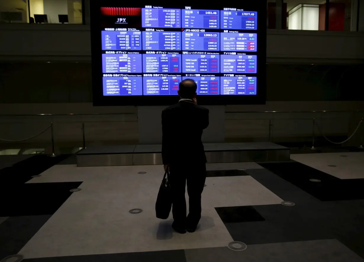 A man looks at an electronic board showing Japan's Nikkei average and related indices at the Tokyo Stock Exchange in Tokyo