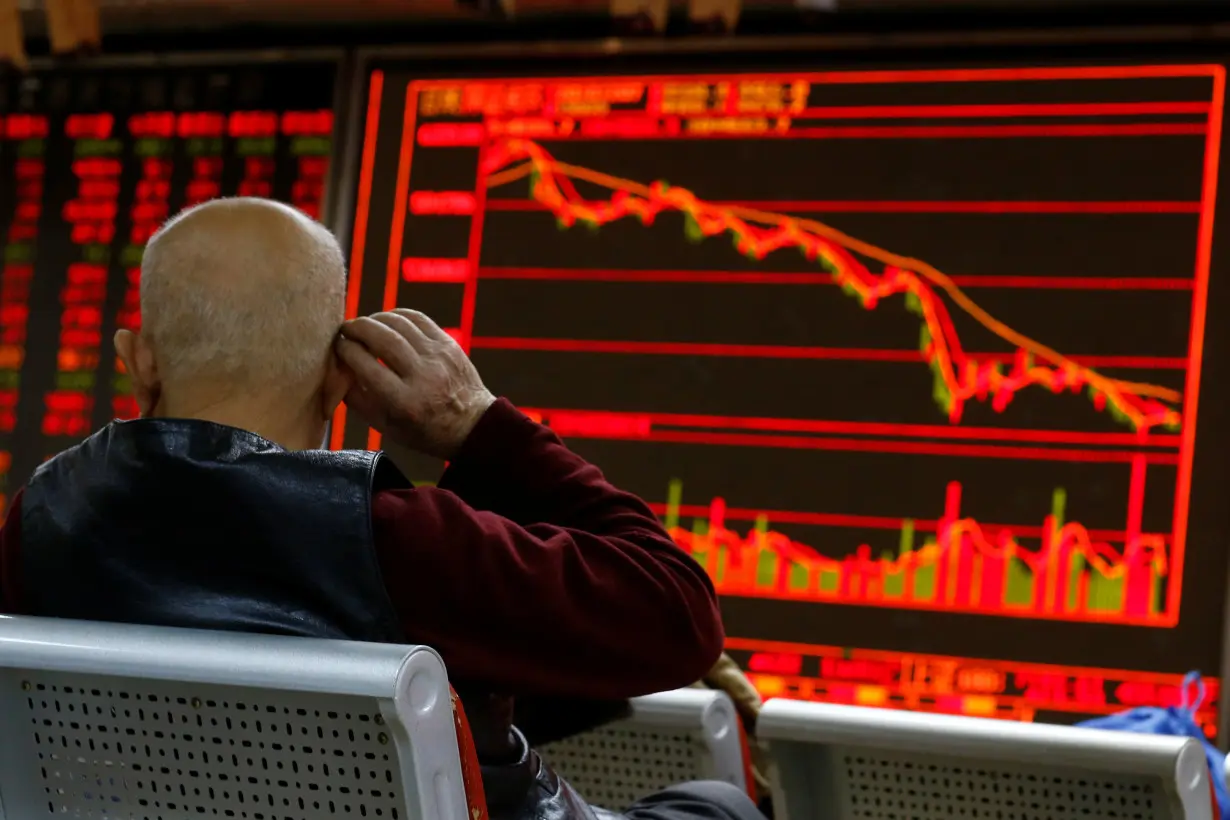 An investor sits in front of a board showing stock information at a brokerage office in Beijing