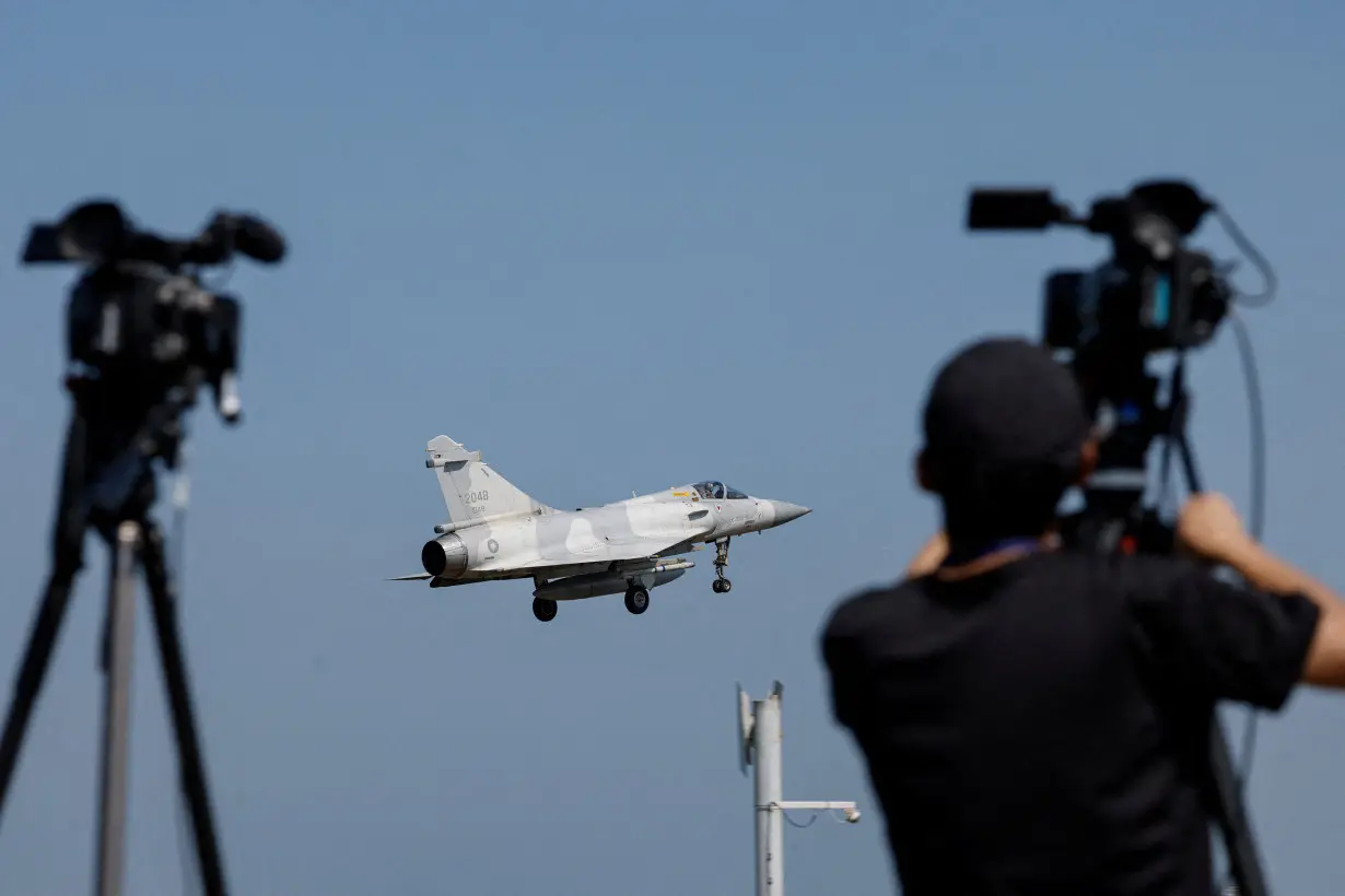 A member of the media takes a video of a Taiwan Air Force Mirage 2000 aircraft preparing to land at Hsinchu Air Base in Hsinchu