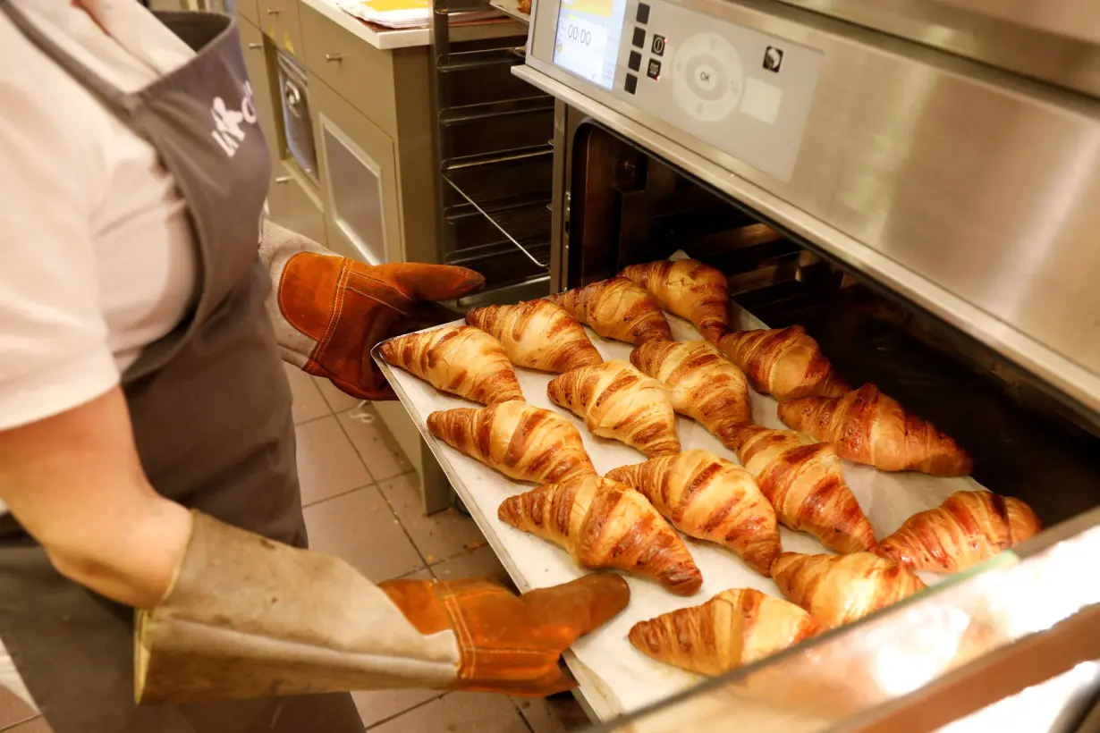 FILE PHOTO: An employee takes out of the oven a tray of croissants at La Croissanterie food chain in Paris