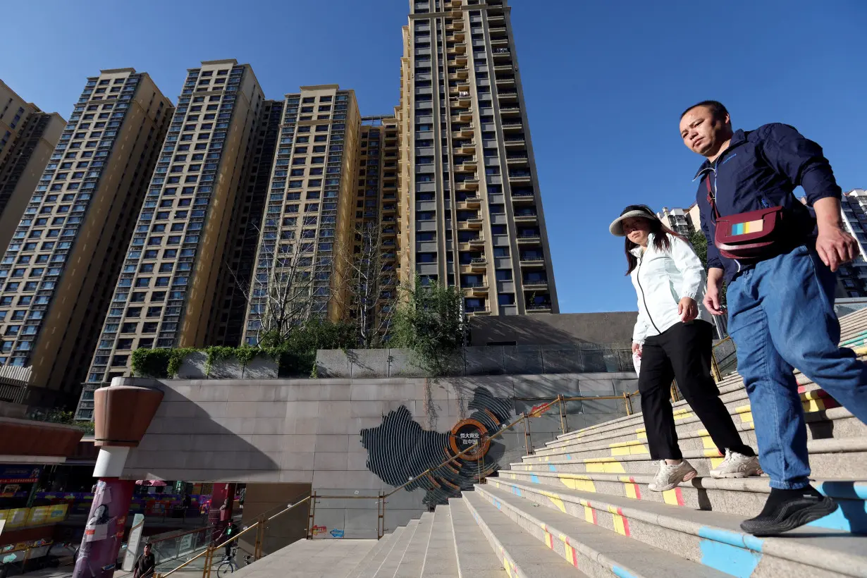 FILE PHOTO: People walk past residential buildings next to the Evergrande City Plaza in Beijing