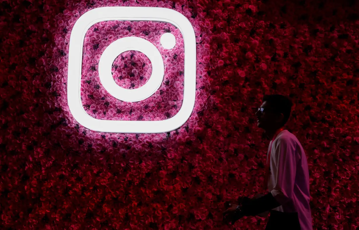 A man walks past a logo of mobile application Instagram, during a conference in Mumbai