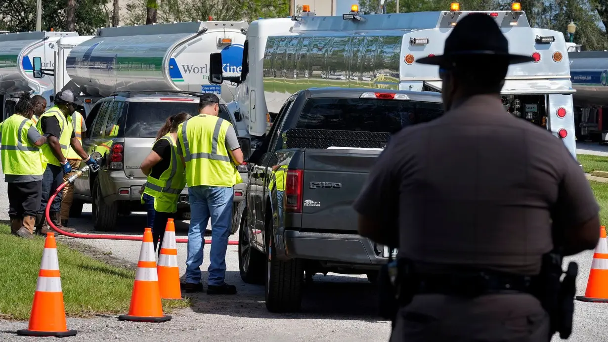 A Florida Highway Patrol officer watches as fuel depot workers distribute gas to residents Saturday, October 12 in Plant City, Florida. Gas stations are slow to reopen after the effects of Hurricane Milton.