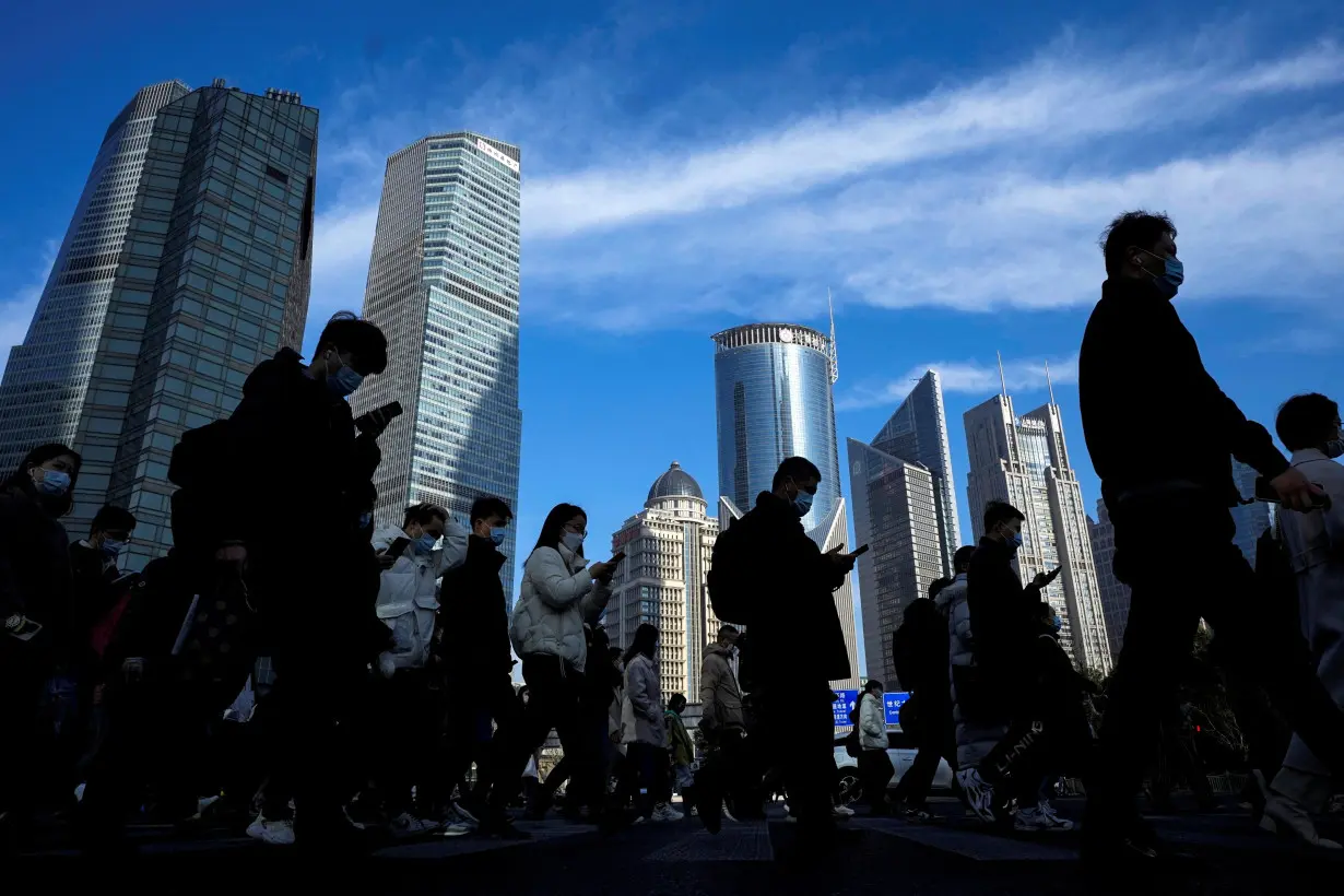 People cross a street near office towers in the Lujiazui financial district, ahead of the National People's Congress (NPC), in Shanghai