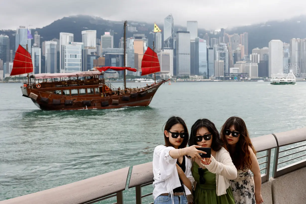 FILE PHOTO: Tourists take photos in front of Victoria Harbour, in Tsim Sha Tsui, in Hong Kong