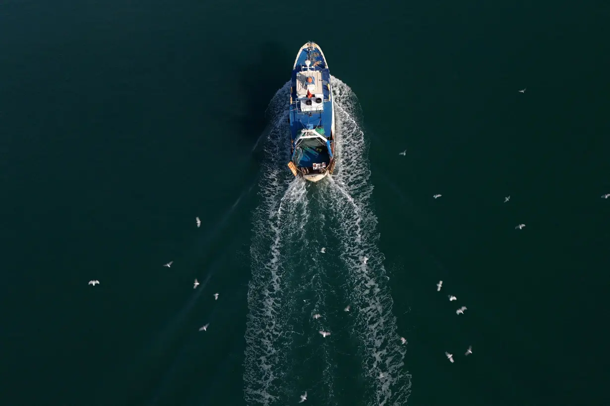 A drone view shows a boat arriving at the port near the reception camp for illegal migrants that would be brought from Italy, in Shengjin