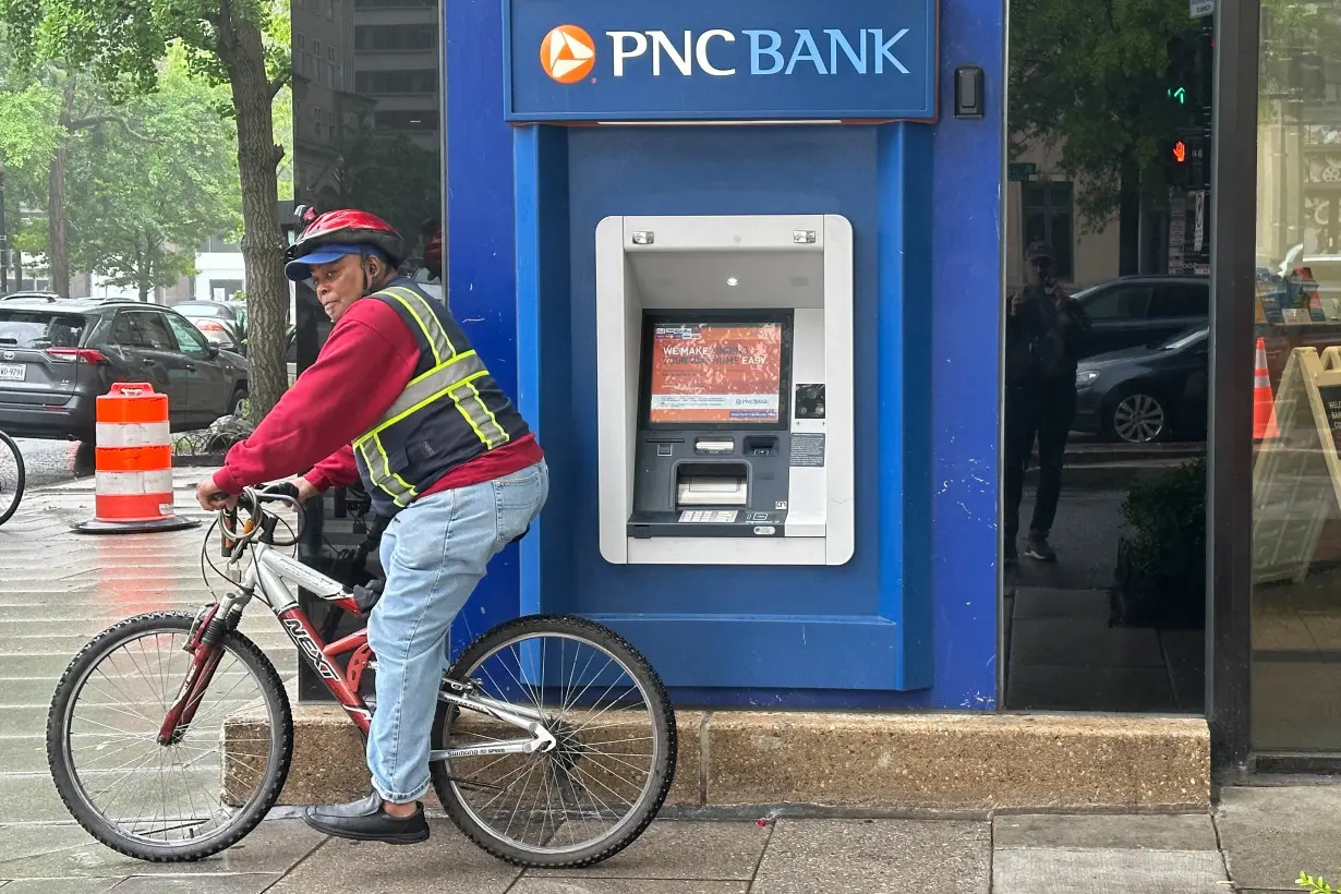 Cyclist stands near a branch of PNC Bank, a subsidiary of PNC Financial Services Group, in Washington