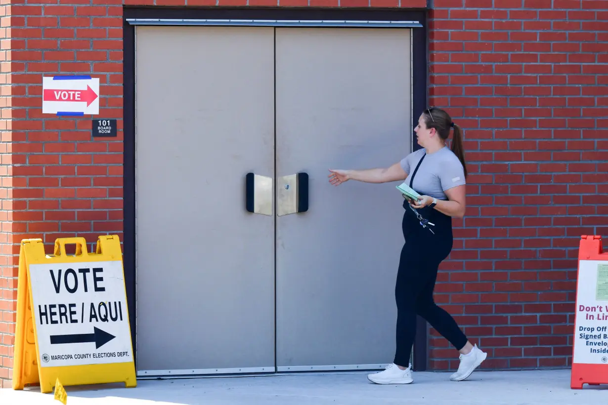 FILE PHOTO: A voter walks into a polling location with her early ballot, in Phoenix