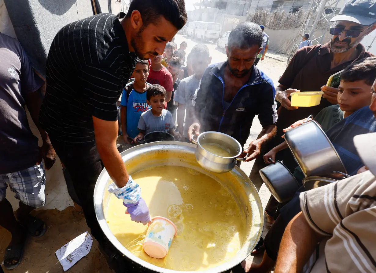 Palestinians gather to receive food cooked by a charity kitchen, in Khan Younis