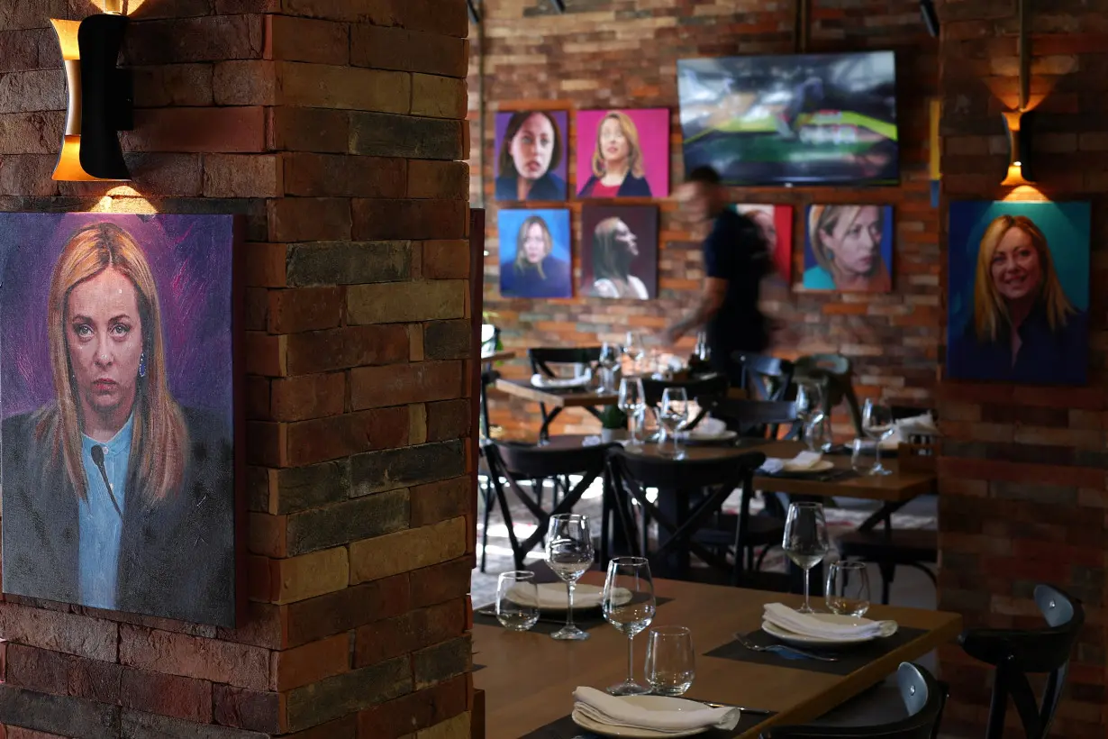 A waiter stands as portrait paintings by artist Helidon Haliti of Italy's Prime Minister Giorgia Meloni are seen on the walls of 