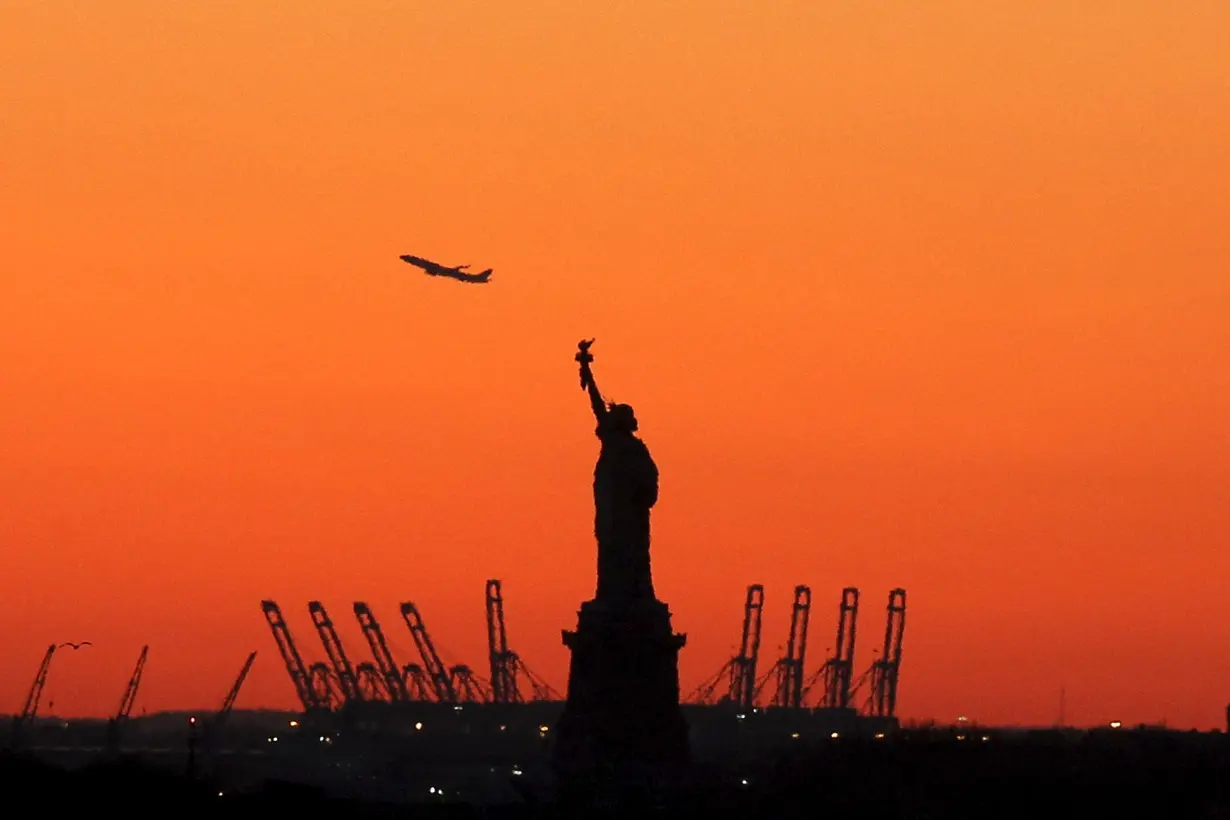 A plane is seen during take off behind the Statue of Liberty in New York's Harbor as seen from the Brooklyn borough of New York