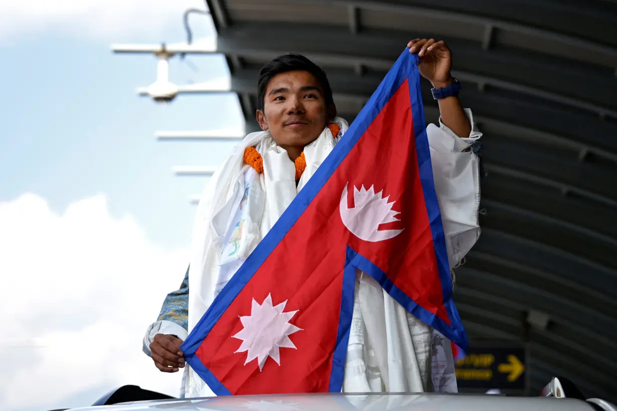 Nima Rinji Sherpa holds a national flag upon his arrival at the airport during a welcoming ceremony in Kathmandu